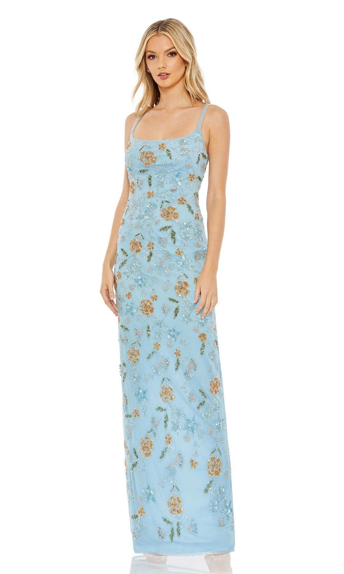 A woman wears the Mac Duggal Long Formal Dress 10808 in light blue with floral patterns, thin straps, and an open back, featuring a fitted silhouette against a white background.